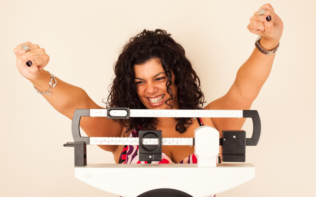 woman with her hands in the air looking happy after weighing herself on the scale