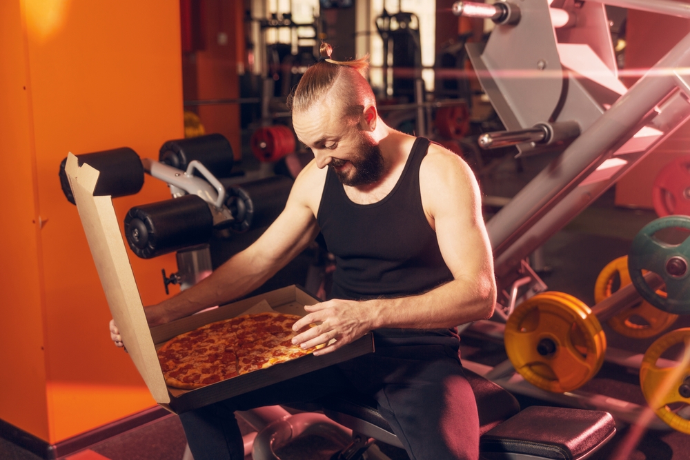 man at the gym starting at a full pizza